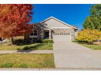 Charming single-story home with stone accents, a well-maintained lawn, and colorful autumn foliage at 23941 E Whitaker Dr, Aurora, CO 80016