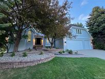 Charming home with a well-manicured lawn, brick accents, mature trees, and a three car garage at 5227 S Geneva St, Englewood, CO 80111