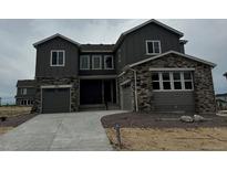 Charming two-story home featuring a stone and gray facade, two-car garage, and well-manicured landscaping at 13765 Emerald Lake St, Parker, CO 80138