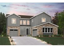 Striking two-story home with stone accents, a well-manicured lawn, and gray siding at 13765 Emerald Lake St, Parker, CO 80138