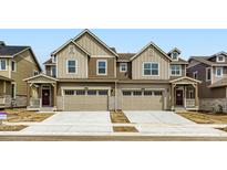 Modern townhome with beige and brown siding, a two-car garage, and a small front porch at 6751 Arbor E Blvd, Thornton, CO 80602