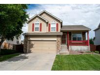 Charming home with two-car garage, covered front porch, red shutters, and a well-manicured lawn at 10534 Ursula St, Commerce City, CO 80022