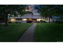 Charming single-story home with mature trees, lush green lawn and inviting walkway at 2250 N Monaco Pkwy, Denver, CO 80207
