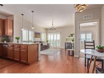 Open-concept living room featuring hardwood floors, modern lighting, and natural light, with a view from the kitchen island at 1162 Rockhurst Dr # 404, Highlands Ranch, CO 80129