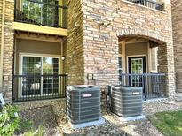 Condo exterior showing stone facade, black railings, and two A/C units at 17346 Nature Walk Trail Trl # 105, Parker, CO 80134