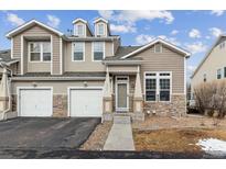 Charming townhome featuring a two-car garage, inviting entryway, and stone accents at 4733 Flower St, Wheat Ridge, CO 80033