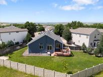 Well-maintained backyard featuring a spacious lawn, a wooden deck, and a modern privacy fence with trees in the background at 6662 Fonder Dr, Parker, CO 80134