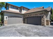 A spacious three-car garage featuring stone accents and ample parking space at 24031 E Hinsdale Pl, Aurora, CO 80016