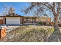 Charming ranch home with brick accents, an attached garage, and mature trees in a well-maintained front yard at 6534 Field St, Arvada, CO 80004