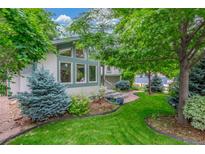 Landscaped front yard with mature trees, flowering shrubs, and manicured lawn at 1080 Tantra Park Cir, Boulder, CO 80305