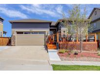 Charming home featuring a two-car garage, stone accents, and a cozy wooden deck with outdoor seating at 18027 Telford Ave, Parker, CO 80134