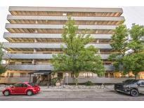 Multi-story apartment building with a lush green tree in front and two cars parked on the street at 1441 N Humboldt St # 504, Denver, CO 80218