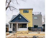 Unique two-story home with a yellow exterior, a rooftop deck, and manicured lawn at 4428 Perry St, Denver, CO 80212