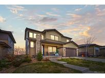Two-story home featuring a manicured lawn, stone accents, and a covered front porch with seating at 14102 Night Owl Ln, Parker, CO 80134