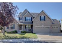 Charming two-story brick home with a well-maintained lawn, three car garage and inviting front porch at 23500 Bent Oaks Way, Parker, CO 80138