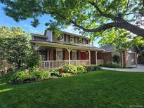 Charming two-story home featuring a welcoming porch, landscaped garden, and lush green lawn, creating inviting curb appeal at 6862 Independence Ct, Arvada, CO 80004