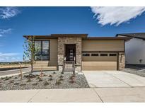 Charming single-story home featuring stone accents, a two-car garage and a well manicured front yard at 400 Basin Daisy St, Castle Rock, CO 80104
