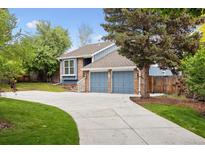 Charming blue two-story home with brick accents, a well-manicured lawn, and a long concrete driveway at 8174 Dudley Cir, Arvada, CO 80005