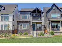 Charming two-story home featuring stone accents, a small balcony, and a well-manicured lawn at 16550 Umatilla Pl, Broomfield, CO 80023