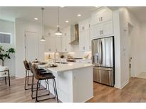 Bright kitchen features white cabinets, stainless steel appliances, and a large quartz island with seating at 16550 Umatilla Pl, Broomfield, CO 80023