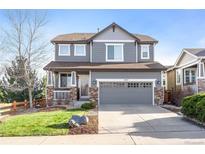 Two-story house with gray siding, stone accents, and a two-car garage at 3087 Black Canyon Way, Castle Rock, CO 80109