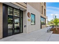 Modern building exterior with glass entryway and adjacent seating area at 3575 Chestnut Pl # 406, Denver, CO 80216