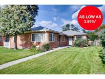 Charming brick home featuring a well-maintained lawn, a quaint walkway, and mature trees, all under a sunny sky at 2028 Perry St, Denver, CO 80212