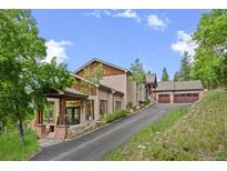 Inviting home exterior with a paved driveway, mature landscaping and stone accents at 12653 Rancho Ct, Conifer, CO 80433