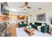 Bright living room featuring stylish green sofas, a ceiling fan, and wood flooring at 9019 E Panorama Cir # D207, Englewood, CO 80112