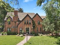 Stately brick Tudor home featuring a lush front lawn, manicured landscaping, and elegant architectural details at 6330 Montview Blvd, Denver, CO 80207