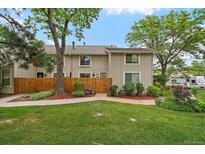 Charming townhome featuring a well-manicured lawn, wood fence, and lush trees, creating a welcoming curb appeal at 6936 S Knolls Way, Centennial, CO 80122