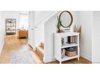 Inviting entryway featuring wood floors, a small bookshelf, and a round mirror at 9542 Cherry St, Thornton, CO 80229