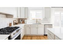 Modern kitchen features white cabinets, stainless steel appliances, gas range, and white tile backsplash at 9542 Cherry St, Thornton, CO 80229
