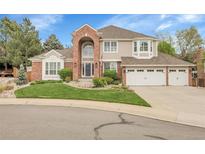 Charming two-story home with a brick facade, arched entryway, three-car garage, and well-manicured front yard at 4220 S Yarrow Ct, Lakewood, CO 80235