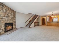 Cozy living room features a stone fireplace and staircase to the upper level at 7474 E Arkansas Ave # 17-07, Denver, CO 80231