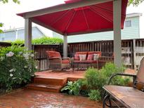 Inviting backyard patio with a red canopy, wicker furniture, and brick pavers, perfect for outdoor relaxation at 742 Mockingbird Ln, Brighton, CO 80601