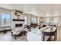 Bright, open living room featuring a modern fireplace, stylish decor, and hardwood floors leading into the kitchen at 1768 Peak Loop, Broomfield, CO 80023