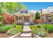 Charming brick home with well-manicured lawn, inviting front porch, and wrought iron fence at 2738 W 38Th Ave, Denver, CO 80211