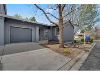 Gray home featuring a garage, walkway, and drought-resistant landscaping in a well-maintained community at 1972 S Carr St, Lakewood, CO 80227