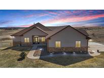 Beautiful ranch home with a stone facade and a well-manicured front yard, captured at sunset at 620 Coyote Trl, Elizabeth, CO 80107