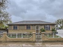 Charming single-story home with a brick and wrought iron fence on a cloudy day at 5481 Xanadu St, Denver, CO 80239