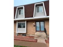 Charming townhome with brick facade, blue door, red rock landscaping, and unique dormer windows at 528 S Youngfield Ct, Denver, CO 80228