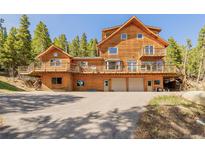 Stunning log home with decks and a two-car garage, surrounded by lush trees and an open driveway at 3581 Gap Rd, Golden, CO 80403