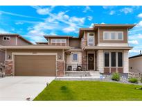 Inviting two-story home featuring a manicured lawn, stone accents, and attached two car garage at 5737 Amarosa Dr, Parker, CO 80134