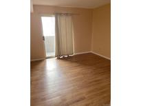 Bright living room with wood-look floors and sliding door to balcony at 5775 W Atlantic Pl # 103, Lakewood, CO 80227