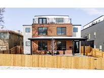 Modern brick home with a rooftop deck and a well-manicured lawn. The wooden fence adds charm at 1683 N Zenobia St, Denver, CO 80204