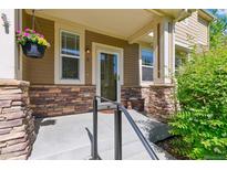 Cozy front porch with stone accents, a hanging flower basket, and a charming entrance to the home at 14247 W 84Th Cir # A, Arvada, CO 80005