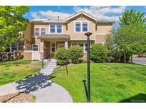 Inviting two-story townhome featuring a landscaped front yard, stone accents, and a charming walkway at 14247 W 84Th Cir # A, Arvada, CO 80005