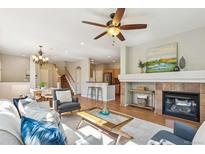 Bright living room features a ceiling fan, fireplace, and an open floorplan to the dining room and kitchen at 14247 W 84Th Cir # A, Arvada, CO 80005