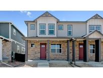 Charming townhome with stone accents, gray siding, and a welcoming front porch at 18724 E 99Th Ave, Commerce City, CO 80022